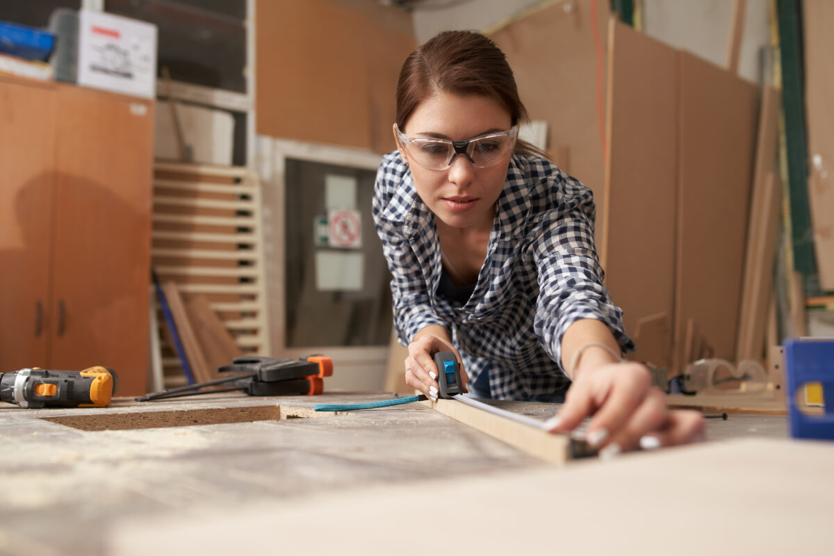 Young woman woodworker with wooden board behind workbench – Bespoke ...